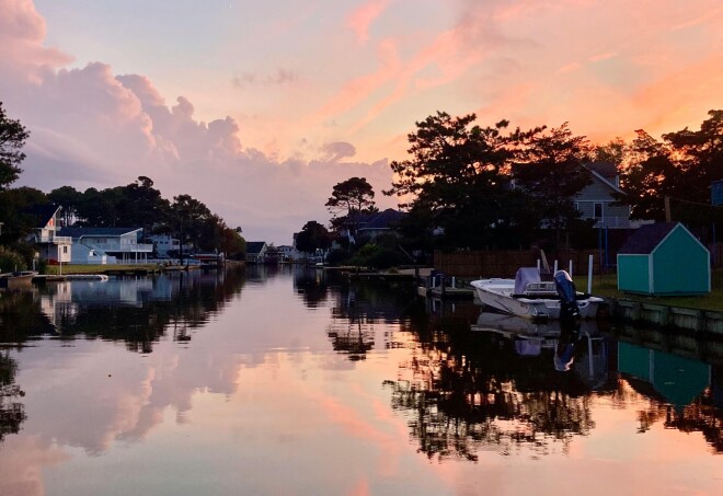 A pastel, cloudy sky reflected in the water at Virginia Beach.