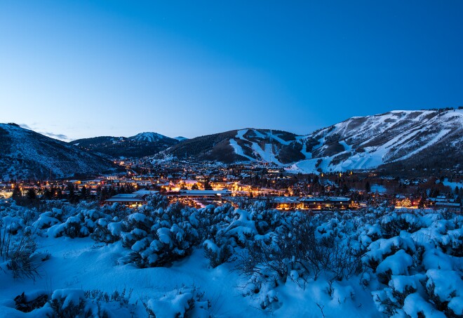 A panoramic view of bright lights in the cool blue snow-covered valley of Park City, Utah at dusk.