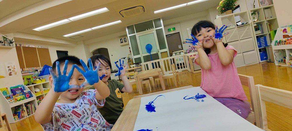 Children at Olivetree International School in Shibuya-ku, Tokyo, participating in a handprint painting activity in the classroom.